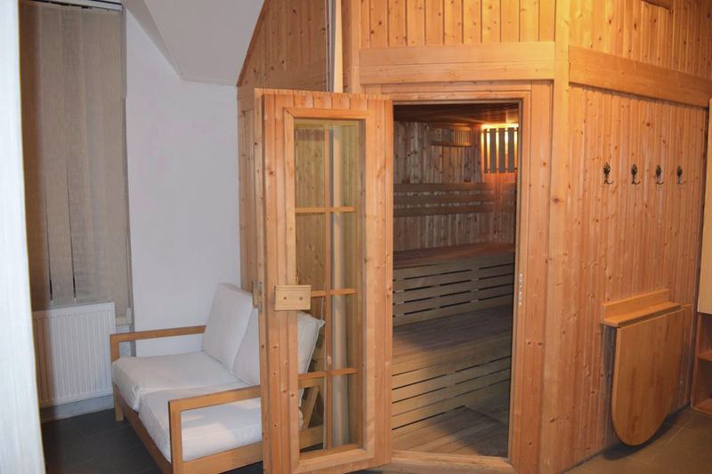 Sauna s otvorenými presklenými dverami a osvetlenými lavicami.
